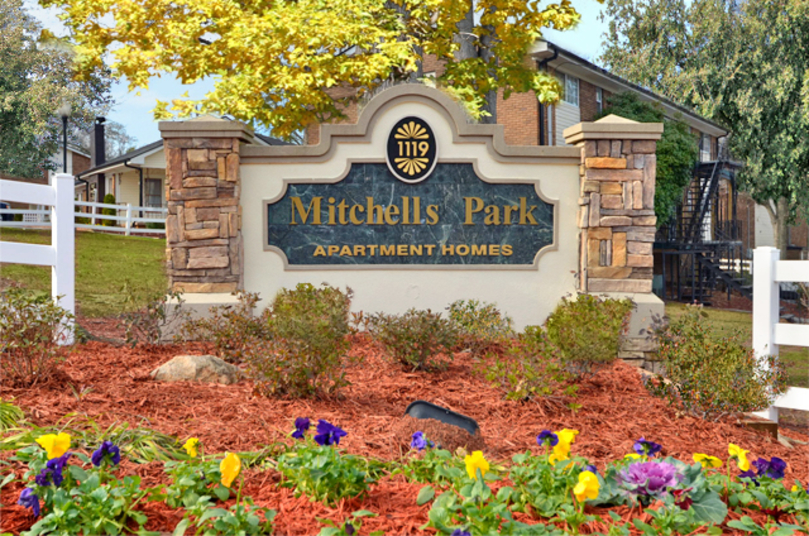 Sign for Mitchell's Park Apartments displayed prominently in the front yard, welcoming residents and visitors alike.